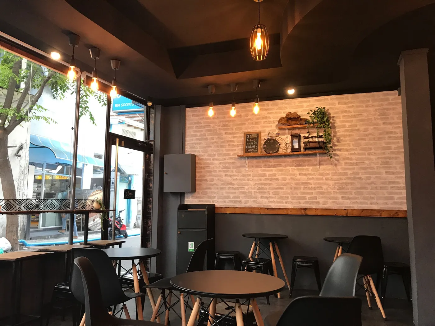 Coffee shop with a brick wall, shelving, and pendant lamps