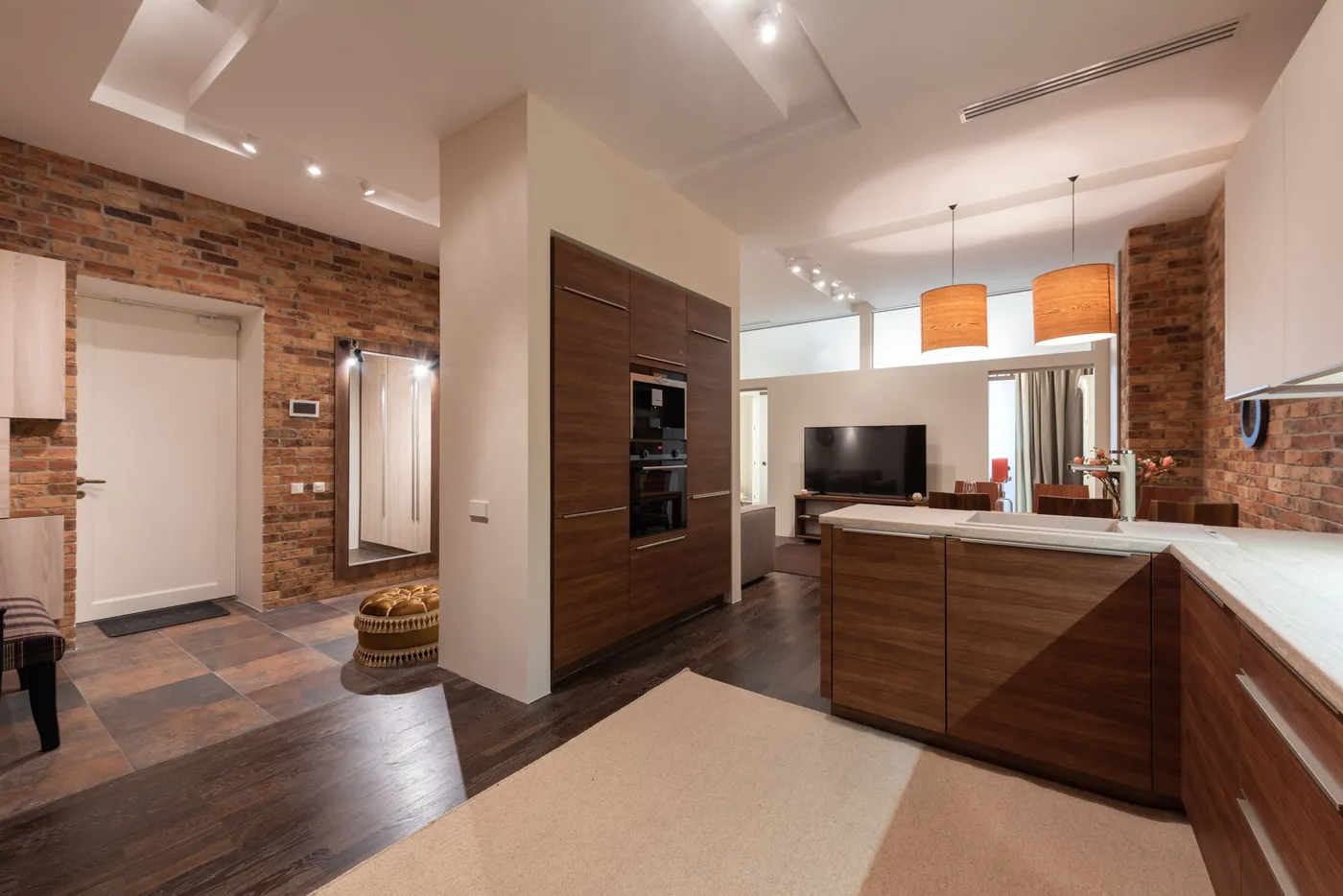 Kitchen with a brick wall and wood cabinets open to the living room