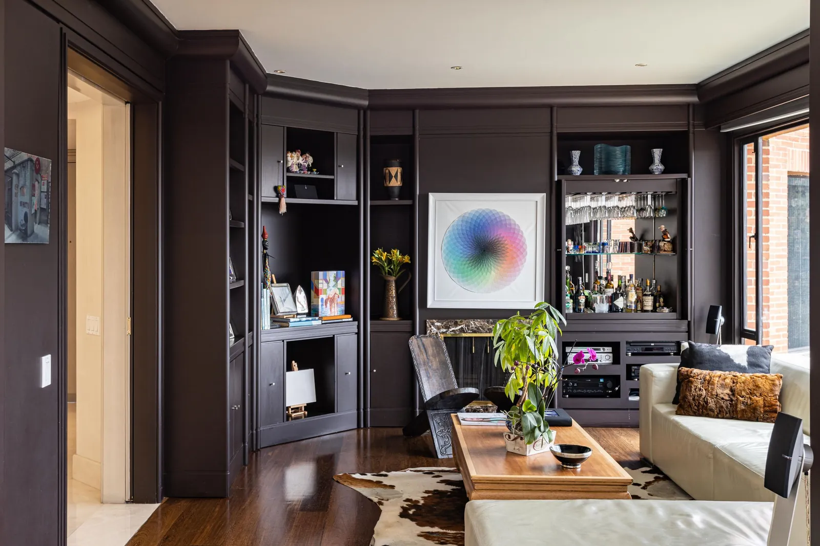 Living room with dark panelled walls, shelving, and lounge chairs