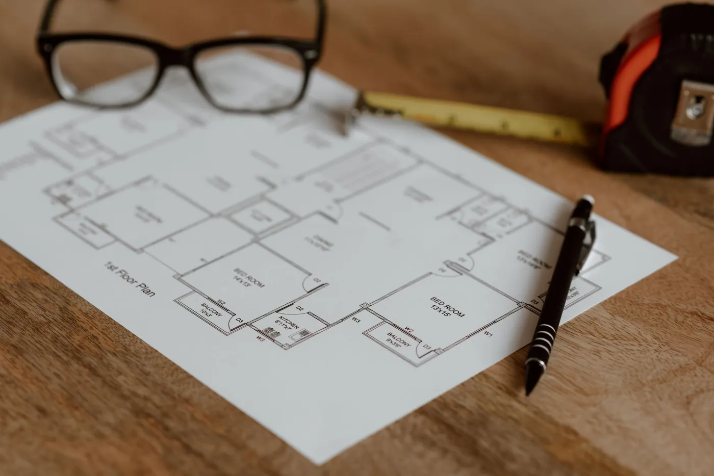 Floor plan drawing on a desk with glasses and a pen