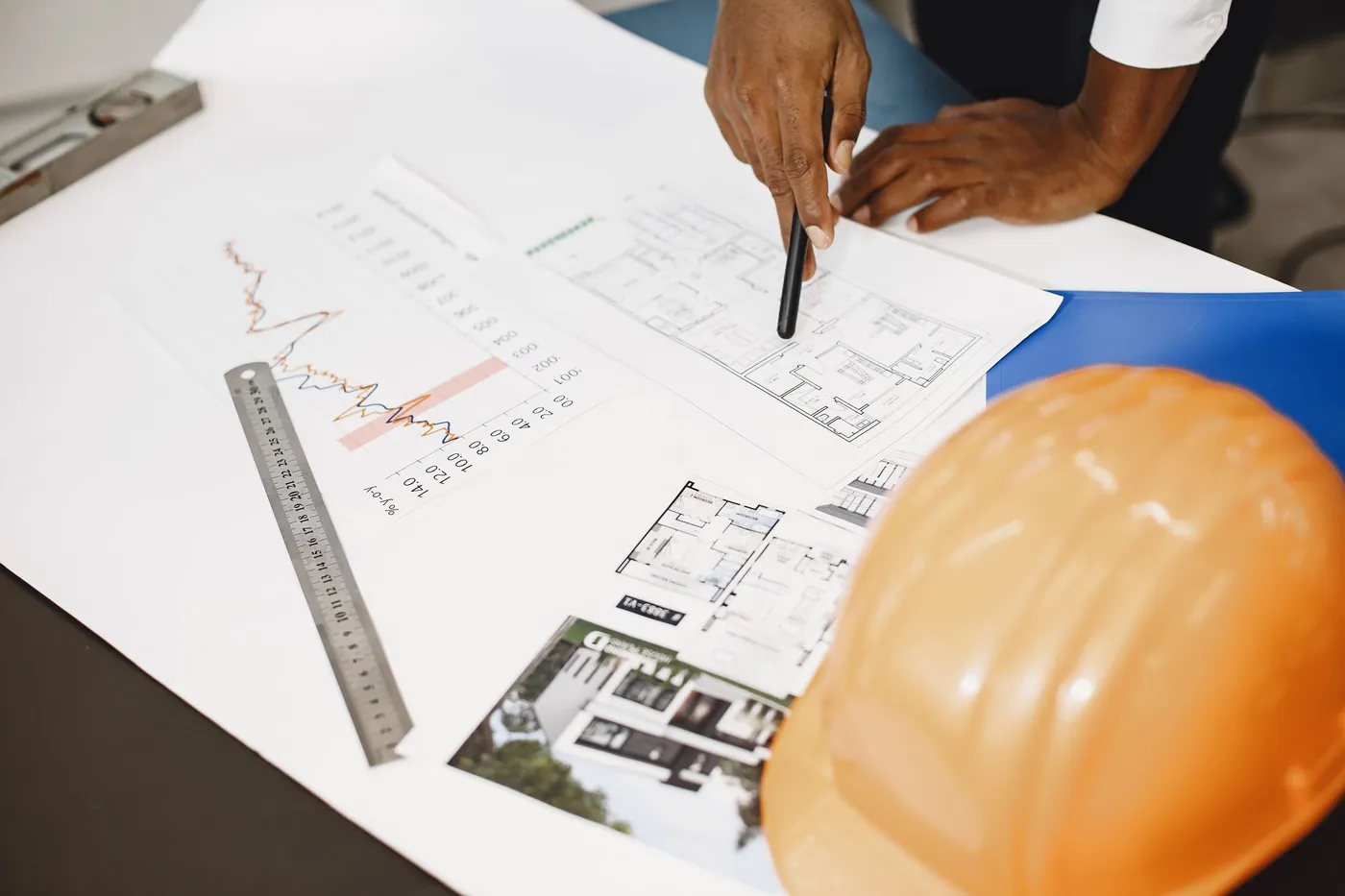 Floor plan drawings on a table with a ruler and a safety helmet